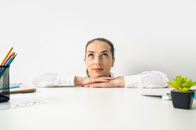 La giovane donna con una maglietta guarda in alto sbirciando da dietro il posto di lavoro