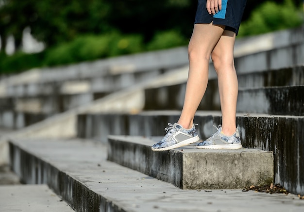 La giovane donna corre in estate in città durante la corsa mattutina Sfondo delle scale