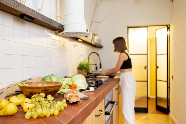 La giovane donna cucina cibo vegetariano sano in cucina a casa