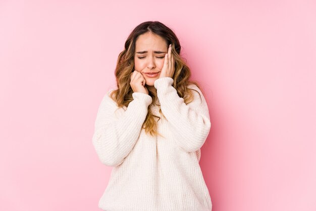 La giovane donna curvy che posa in una parete rosa ha isolato piagnucolando e gridando sconsolato.