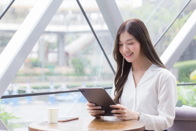 La giovane donna d'affari asiatica professionale sta guardando un tablet o un blocco note nelle sue mani