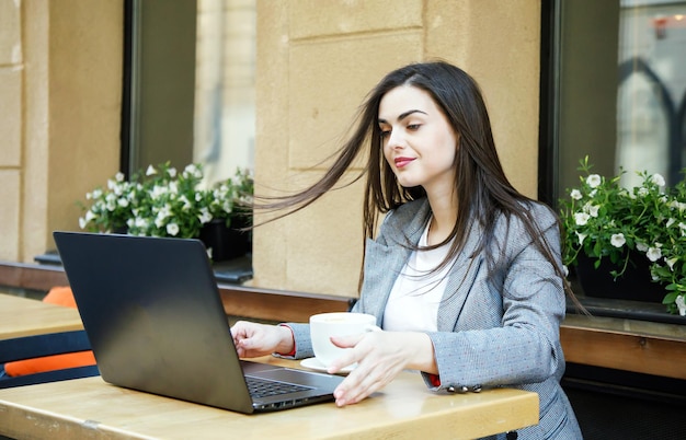 La giovane donna d'affari di successo ha iniziato a lavorare con il laptop dopo la pausa caffè alla caffetteria di strada