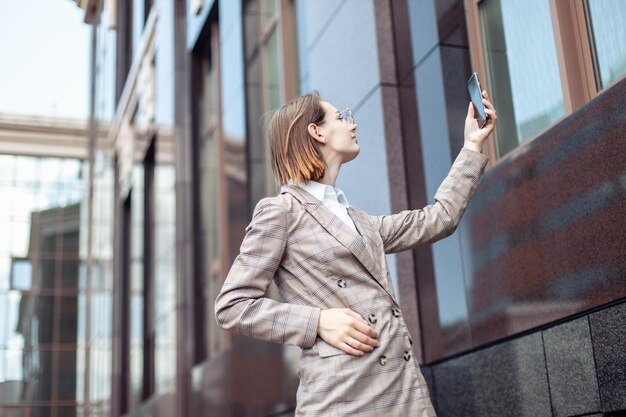 La giovane donna d'affari moderna cattura la comunicazione alzando la mano con uno smartphone in città Cattiva connessione