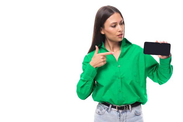 La giovane donna dai capelli castani dai capelli castani con il trucco in una camicetta verde mostra annunci su un orizzontale