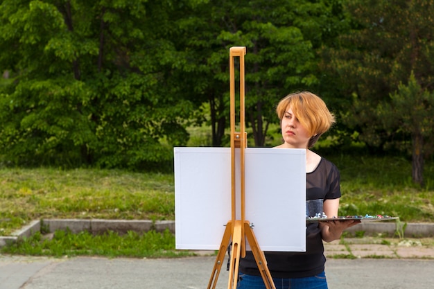 La giovane donna dell'artista dipinge su una tela un paesaggio urbano