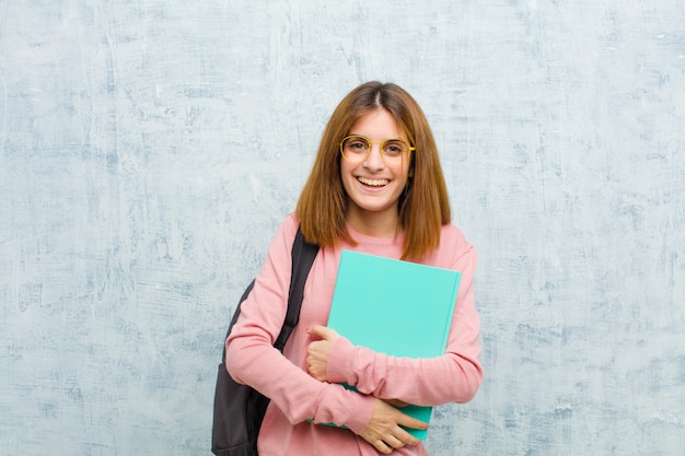 La giovane donna dello studente che assomiglia ad un realizzatore felice, fiero e soddisfatto che sorride con le armi ha attraversato contro il lerciume