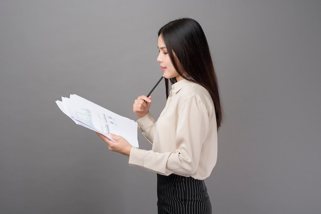 La giovane donna di affari sta analizzando il business plan su fondo grigio