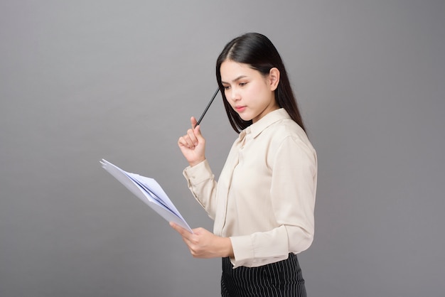 La giovane donna di affari sta analizzando il business plan su fondo grigio