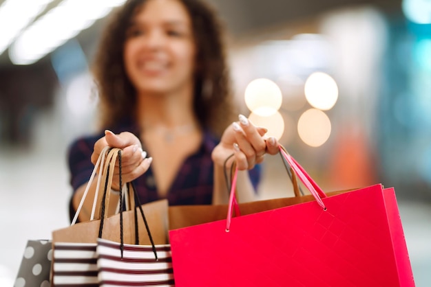 La giovane donna dopo lo shopping con le borse della spesa cammina nel centro commerciale Shoopping primaverile