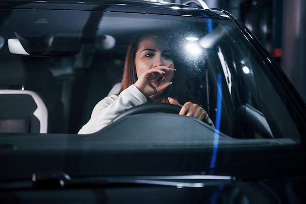 La giovane donna è all'interno di un'automobile moderna nuova di zecca.