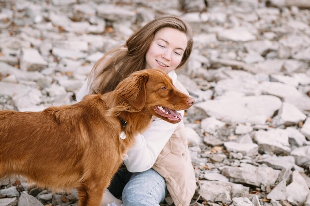 La giovane donna e il cane da riporto camminano sulla riva del fiume alla stagione autunnale