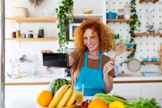 La giovane donna è in cucina, ha le cuffie wireless, balla e canta