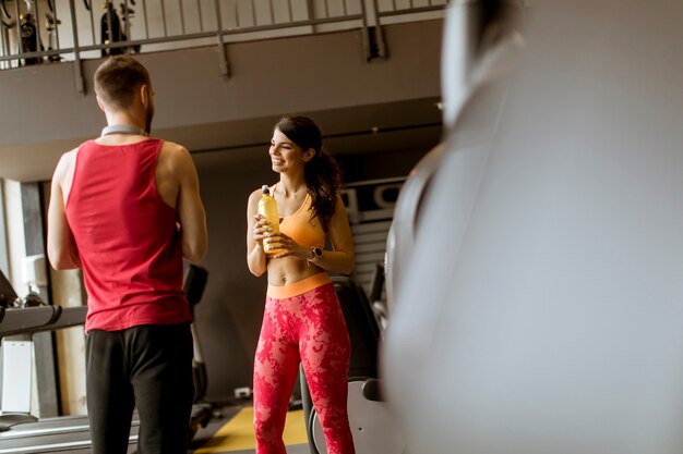 La giovane donna e l&#39;istruttore personale riposano in palestra dopo l&#39;allenamento