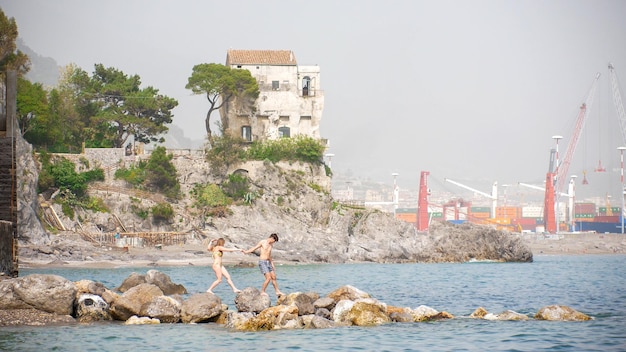 La giovane donna e l'uomo camminano lungo le rocce nel mare