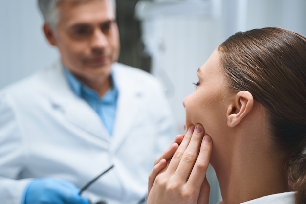 La giovane donna è seduta in una clinica dentistica e si lamenta dei problemi in bocca con un medico esperto