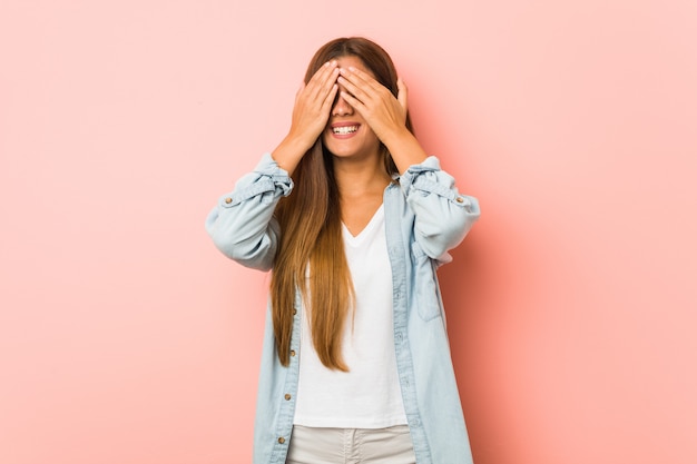 La giovane donna esile copre gli occhi con le mani, sorride ampiamente aspettando una sorpresa.