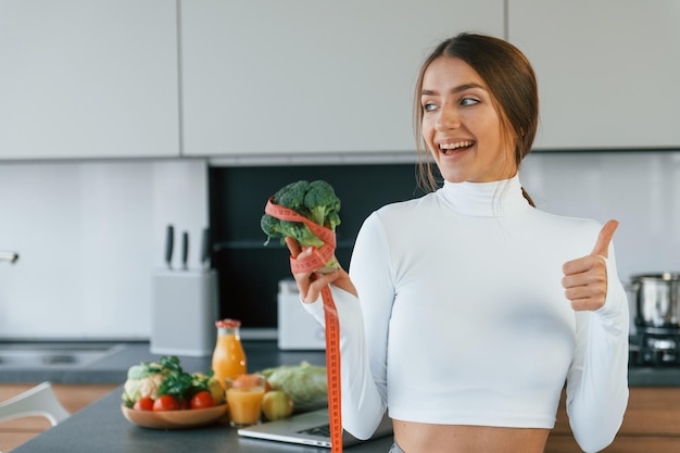 La giovane donna europea è al chiuso in cucina al chiuso con cibo sano