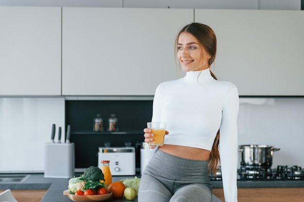 La giovane donna europea è al chiuso in cucina al chiuso con cibo sano