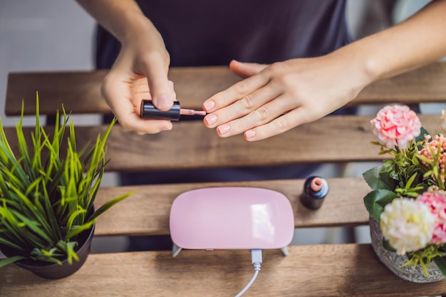 La giovane donna fa la manicure con smalto gel e lampada UV in tonalità rosa