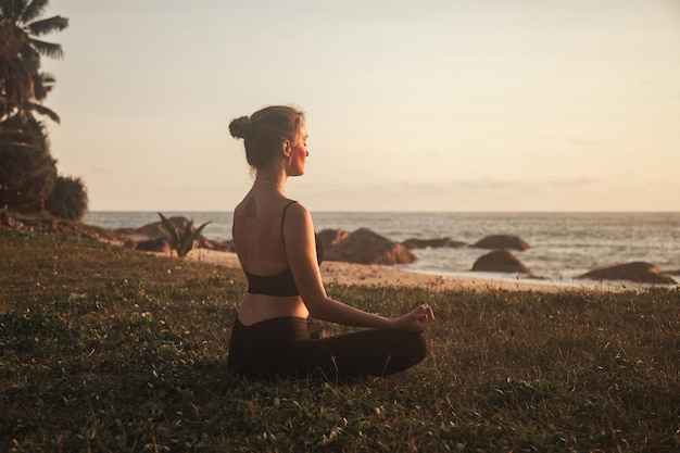 La giovane donna fa yoga per uno stile di vita sano sulla spiaggia del mare