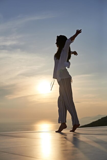 la giovane donna felice si gode il tramonto mentre balla e ascolta la musica con le cuffie