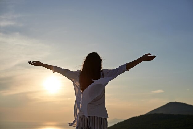 la giovane donna felice si gode il tramonto mentre balla e ascolta la musica con le cuffie