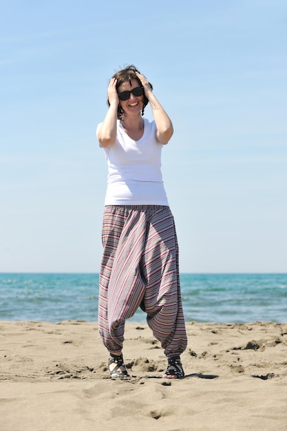 la giovane donna felice si rilassa sulla bellissima spiaggia al fresco mattino d'estate e si gode il primo raggio di sole