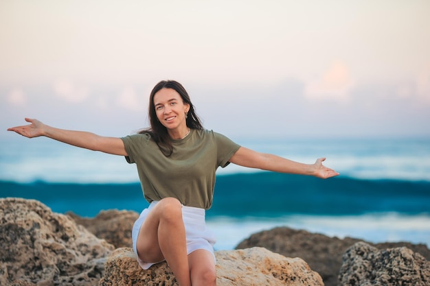 La giovane donna felice sulla spiaggia si gode le sue vacanze estive