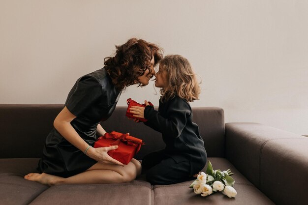 La giovane donna graziosa con la sua figlia carina si sta regalando a vicenda nel giorno della donna