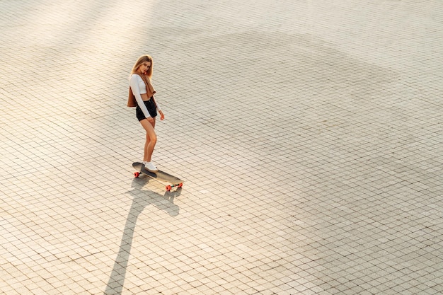 La giovane donna guida una foto di alta qualità di longboard