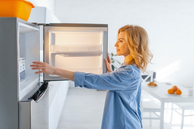 La giovane donna ha aperto il frigorifero in cucina.