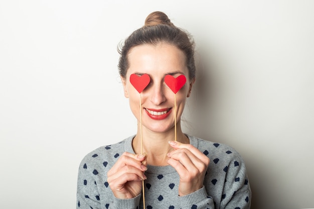 La giovane donna ha chiuso gli occhi con i cuori sui bastoni su uno sfondo chiaro. San Valentino, compleanno. Banner.