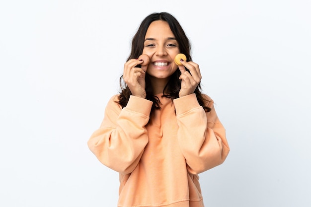 La giovane donna ha isolato lo sfondo bianco che tiene i macarons francesi colorati e sorride