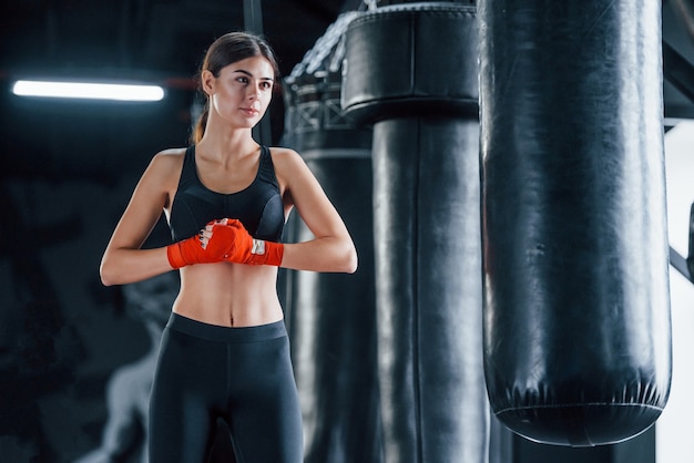 La giovane donna in abbigliamento sportivo è in palestra con una giornata di esercizio. Concezione della boxe.