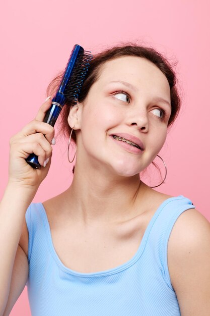 La giovane donna in magliette blu pettina con le emozioni dei capelli ha isolato lo sfondo inalterato