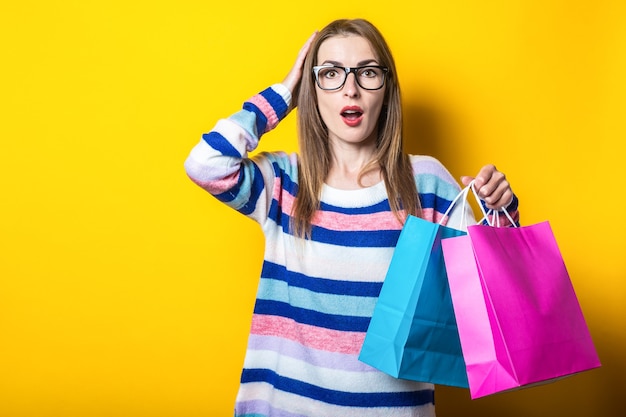 La giovane donna in maglione tiene i sacchetti della spesa