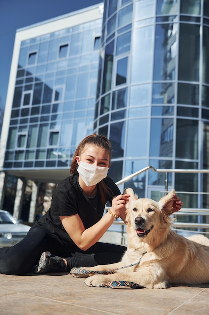 La giovane donna in maschera protettiva fa una passeggiata all'aperto vicino all'edificio aziendale al momento della quarantena Concezione del coronavirus