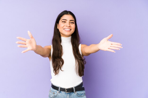 La giovane donna indiana isolata sulla parete viola si sente sicura di dare un abbraccio a