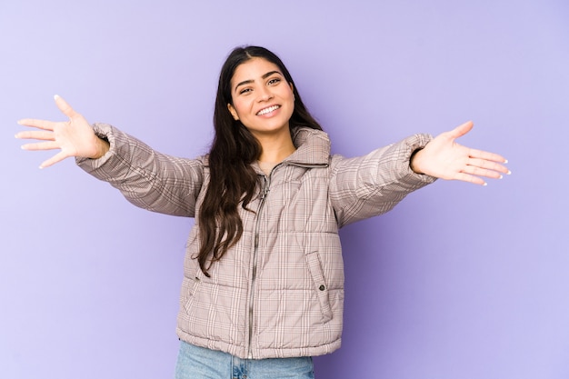 La giovane donna indiana isolata sulla parete viola si sente sicura di dare un abbraccio a