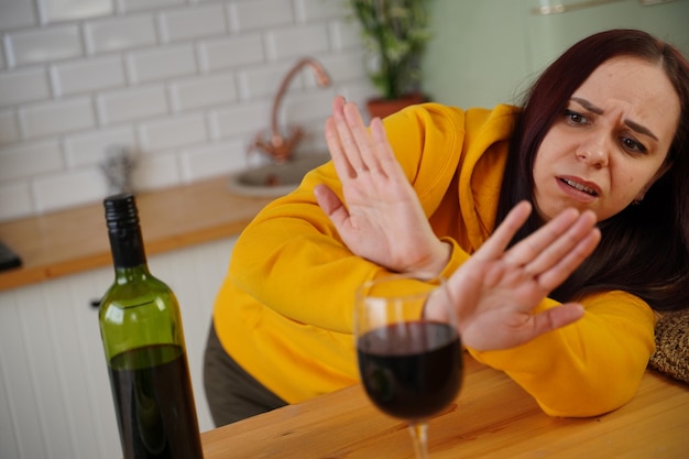 La giovane donna infelice ha mal di testa da vino rosso La femmina adulta si sente male dall'alcol mentre è in cucina