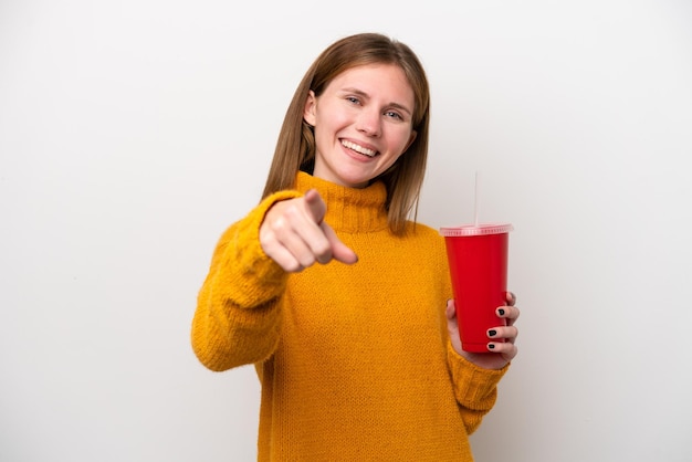 La giovane donna inglese che tiene la soda isolata su sfondo bianco punta il dito contro di te con un'espressione sicura