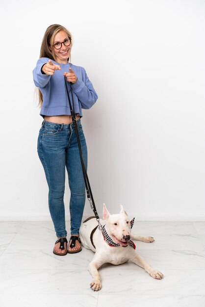 La giovane donna inglese con il suo cane isolato su sfondo bianco ti punta il dito contro con un'espressione sicura