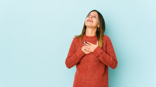 La giovane donna isolata sulla parete blu ha un'espressione amichevole, premendo il palmo contro il petto. Concetto di amore.