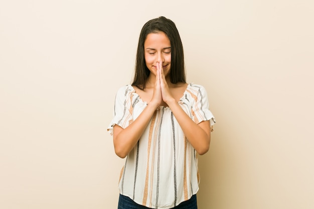 La giovane donna ispanica che si tiene per mano dentro prega vicino alla bocca, si sente sicura.