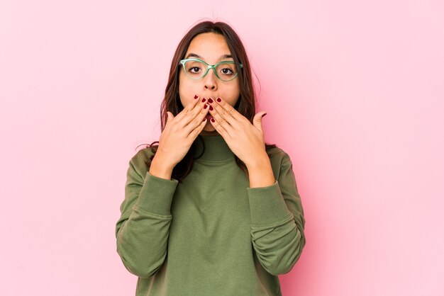 La giovane donna ispanica di razza mista ha isolata la bocca scioccata della copertura con le mani.