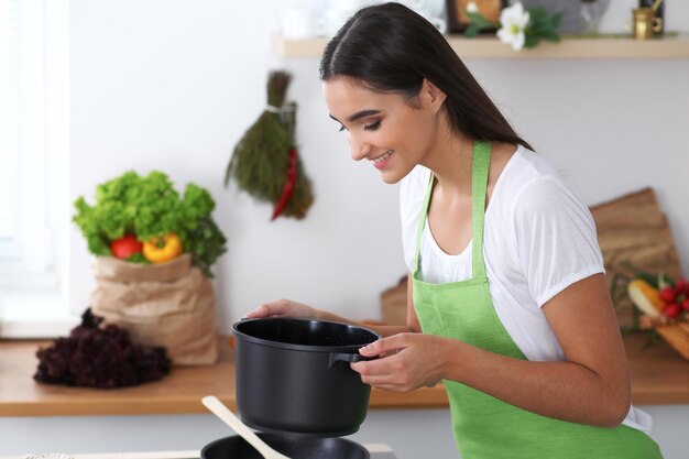 La giovane donna ispanica sta cucinando in cucina