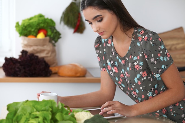 La giovane donna ispanica sta facendo acquisti online tramite tablet e carta di credito La casalinga ha trovato una nuova ricetta per cucinare in cucina