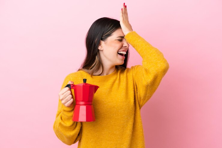Foto la giovane donna italiana che tiene in mano una caffettiera isolata su sfondo rosa ha realizzato qualcosa e intendeva la soluzione