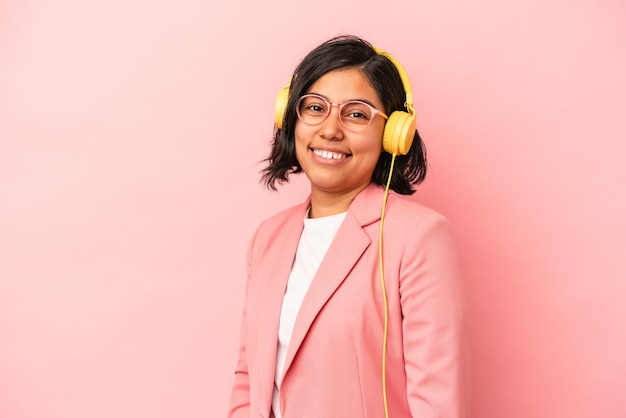 La giovane donna latina che ascolta la musica isolata su fondo rosa sembra da parte sorridente, allegra e piacevole.