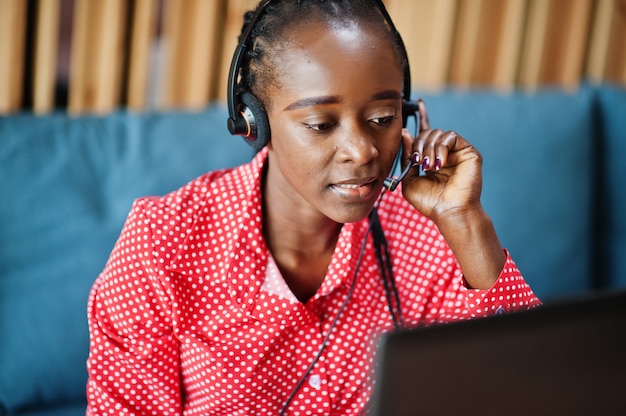 La giovane donna lavora in un operatore di call center e un agente del servizio clienti che indossa cuffie con microfono che lavorano su laptop